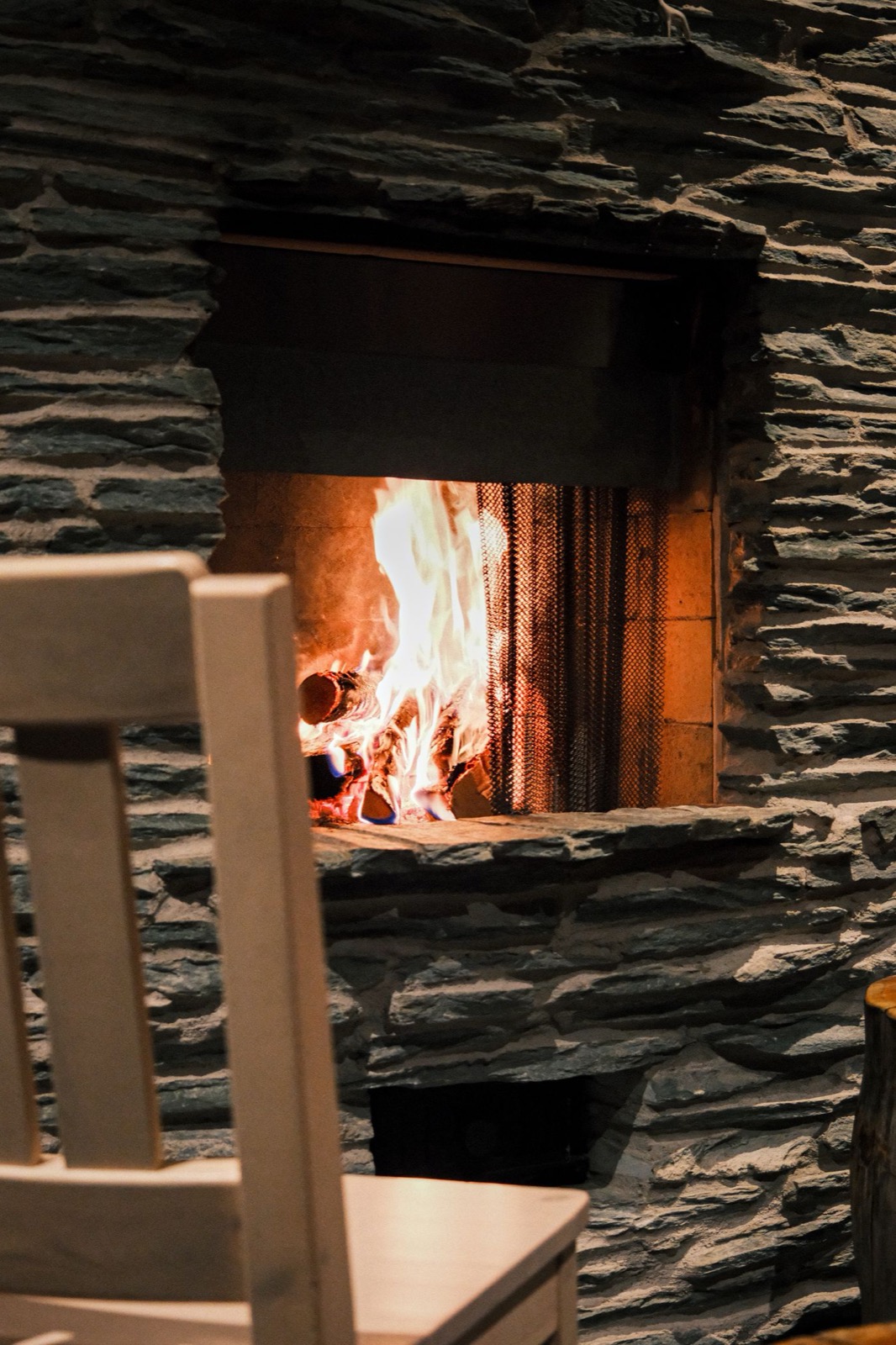 Cheminée insérée dans un mur d'ardoise avec belle flambée